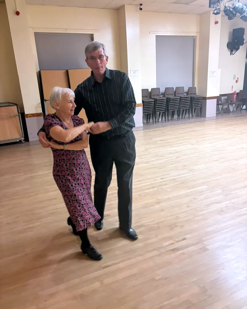 A smiling couple practising a turn in class